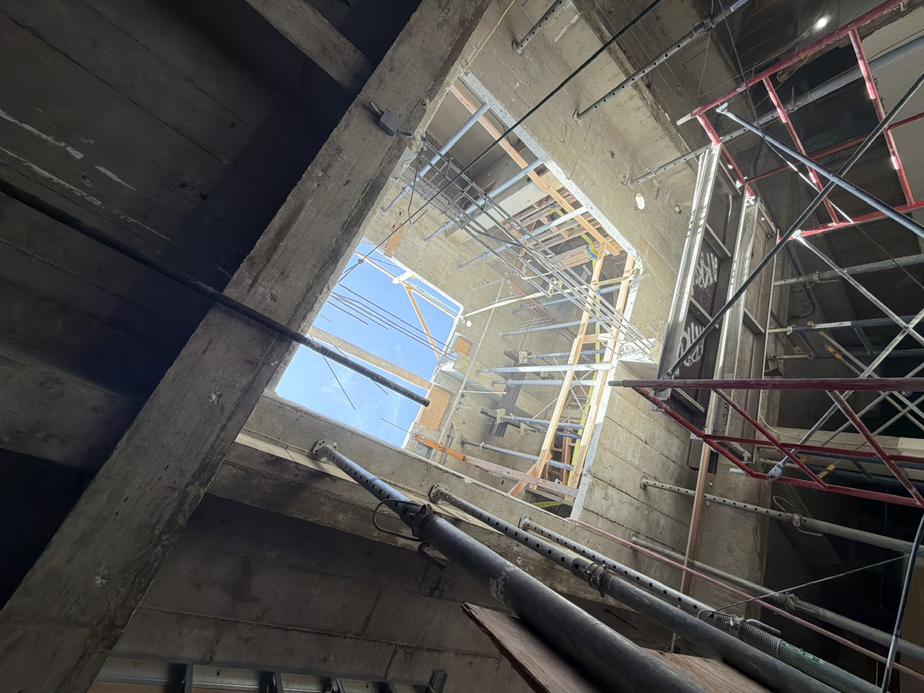 Newly cut elevator shaft opening through the existing concrete floor, viewed from below